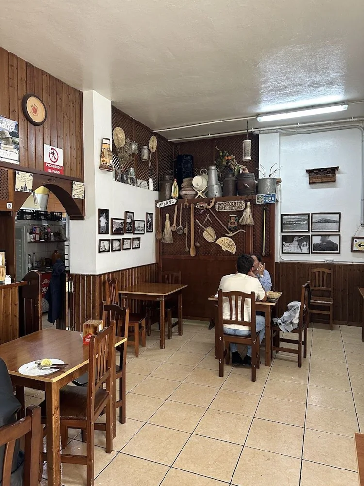 Mesas, sillas de madera y barra en el interior del guachinche